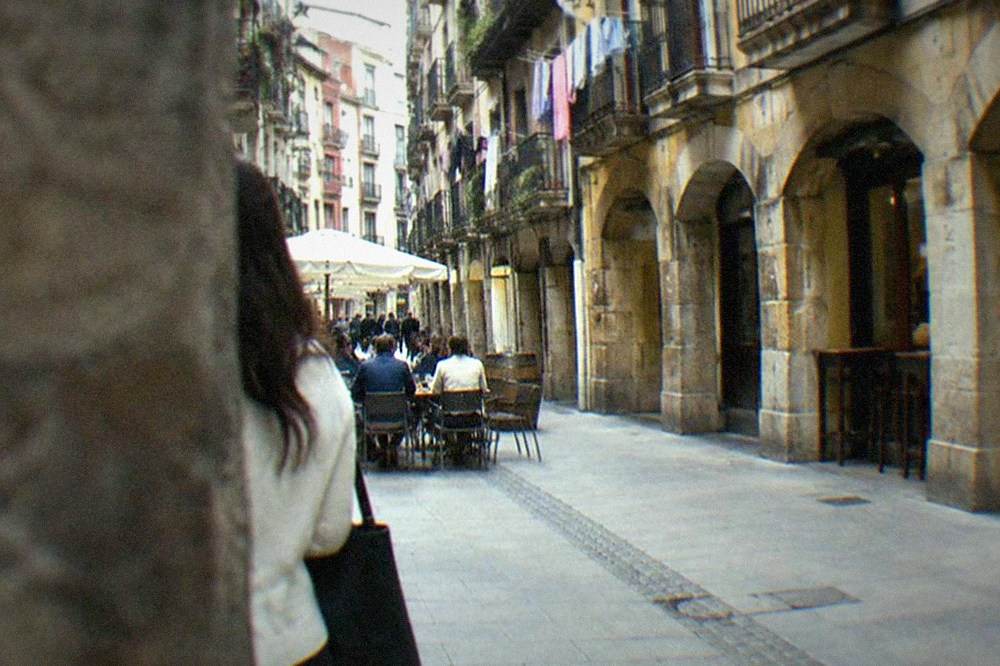Narrow medieval street in Bilbao's Casco Viejo with cafe tables and hanging laundry