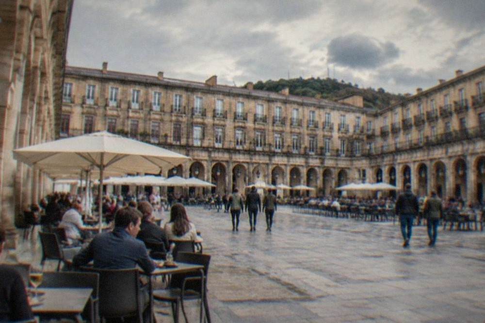 The arcaded Plaza Nueva in Bilbao's old town with people seated at outdoor pintxos bars