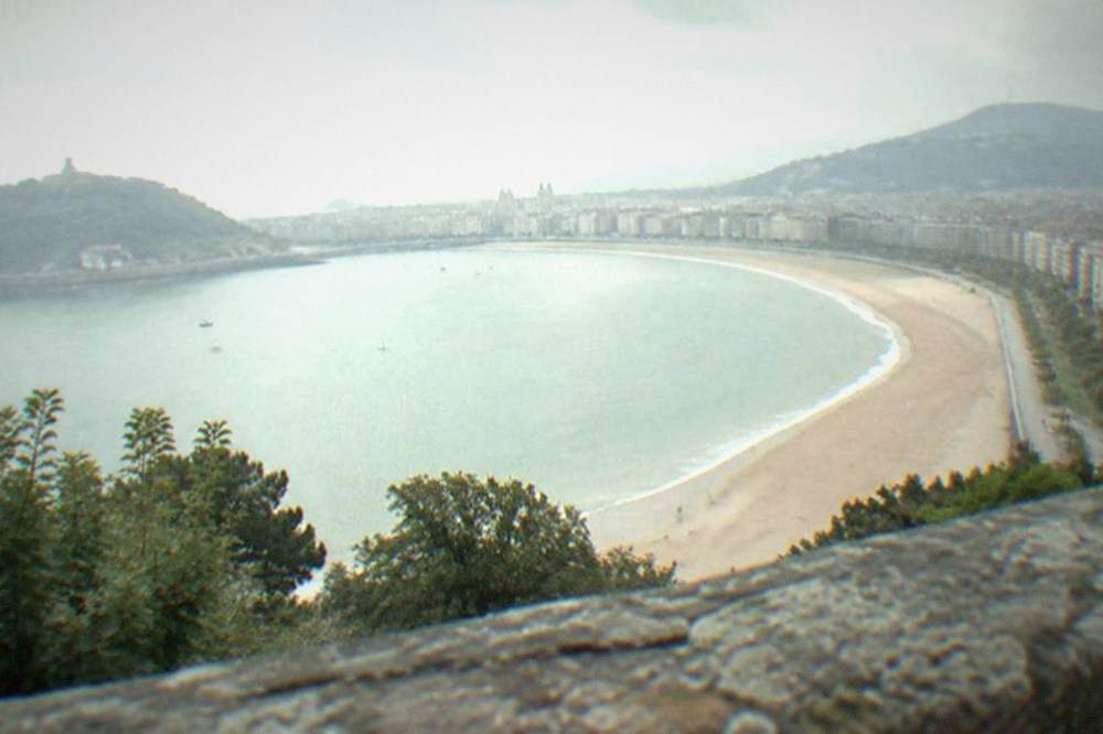 The curved sandy beach of La Concha in San Sebastián seen from a hillside viewpoint