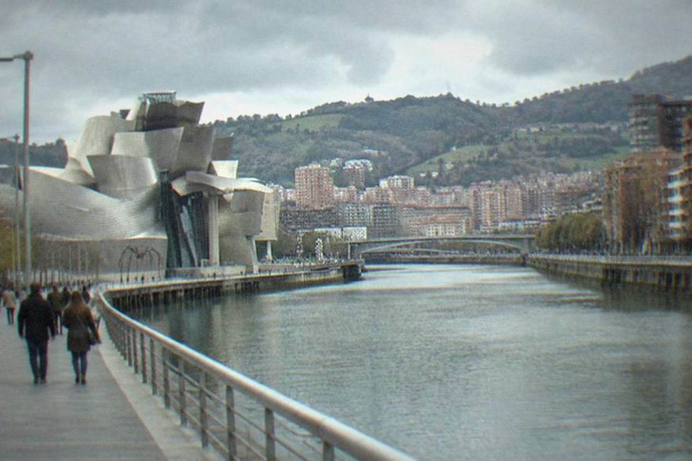 Visitors strolling the Abandoibarra riverside promenade with the Guggenheim behind them