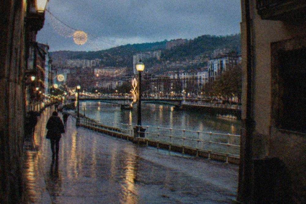 Wet cobblestone street in the Bilbao Old Town with Christmas lights reflecting in puddles