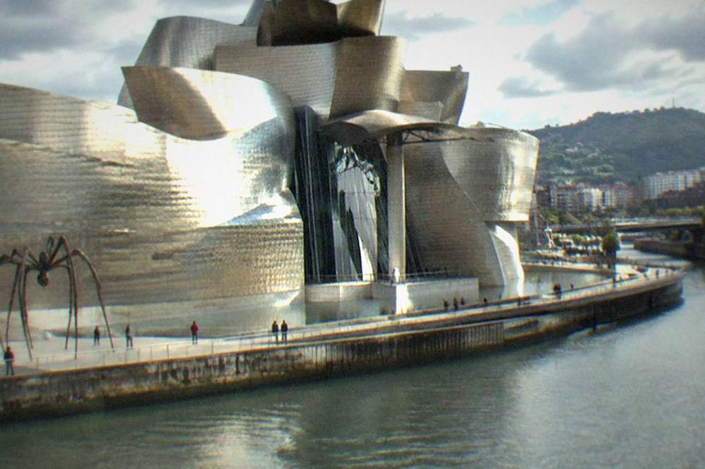 Visitors looking at large modern art installations inside the Guggenheim Museum Bilbao