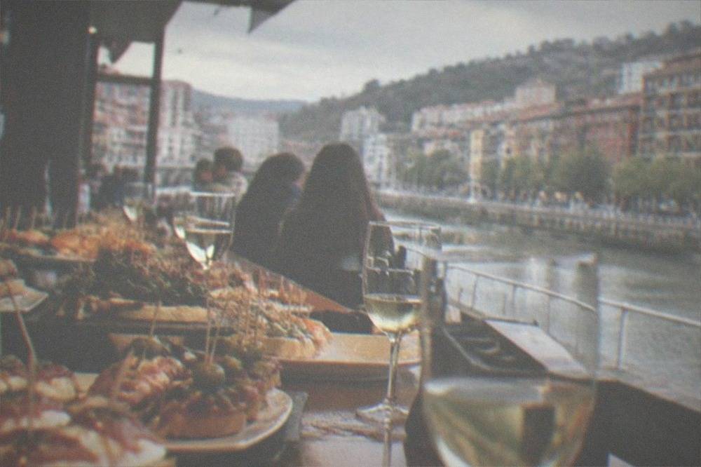 Crowded pintxos bar counter in Bilbao loaded with small skewered snacks and glasses of wine