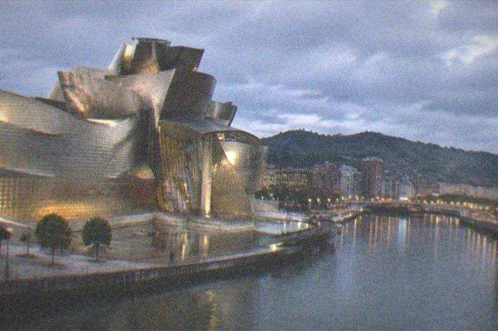 Evening view over Bilbao with the illuminated Guggenheim Museum beside the dark river