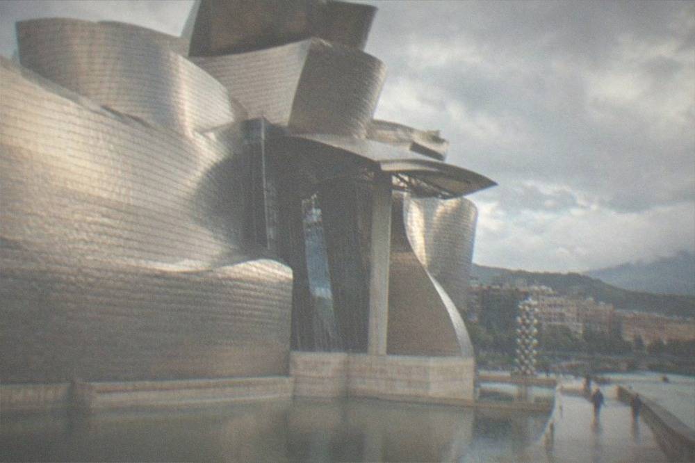 The titanium curved exterior of the Guggenheim Museum Bilbao beside the river on a bright day