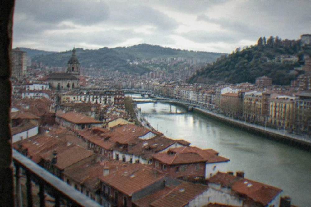 A view over red rooftops and a river in Bilbao's old town on an overcast day