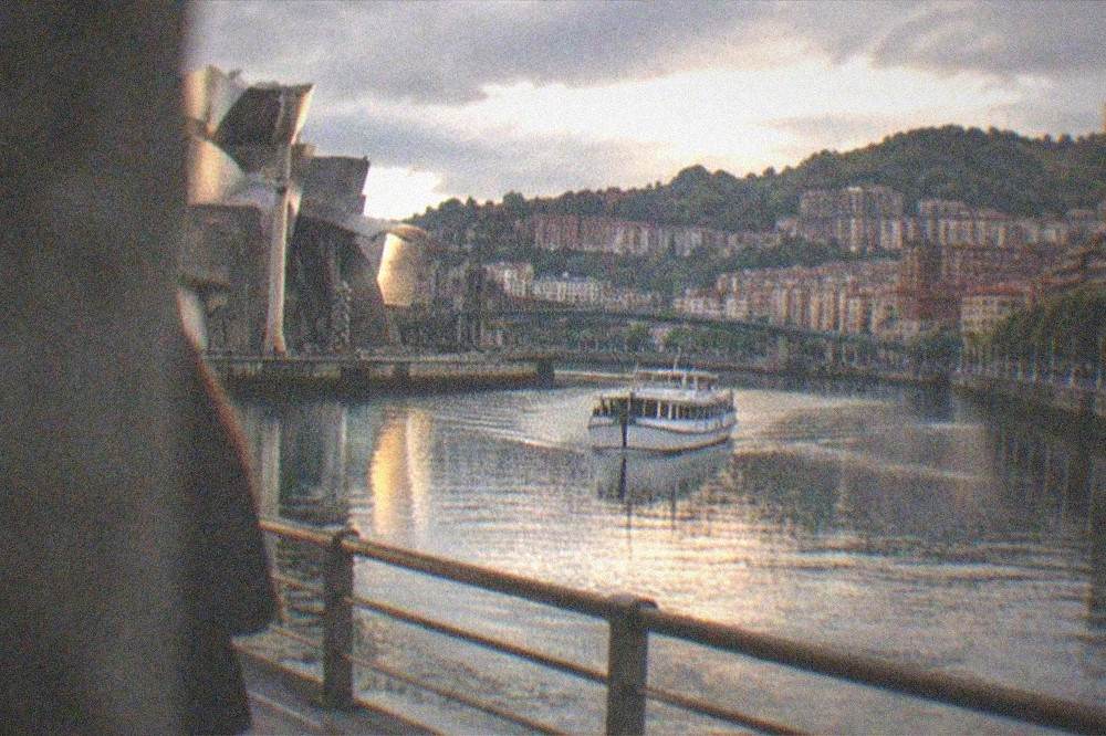Evening light on the Bilbao estuary with a boat and city buildings reflected in the water