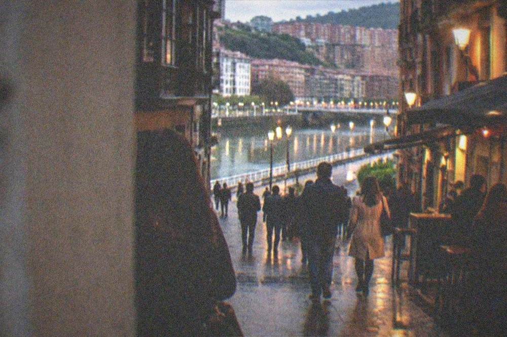 Evening view of a lit bar street in central Bilbao with people walking