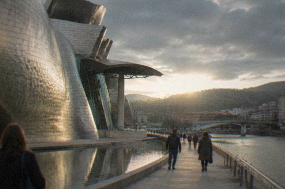 Visitors walking beside the reflective titanium curves of the Guggenheim Museum Bilbao