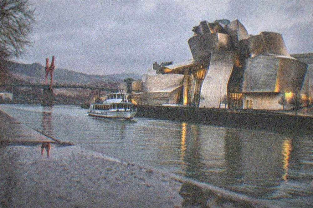 The illuminated Guggenheim Museum reflected in the calm Nervion estuary at dusk in winter