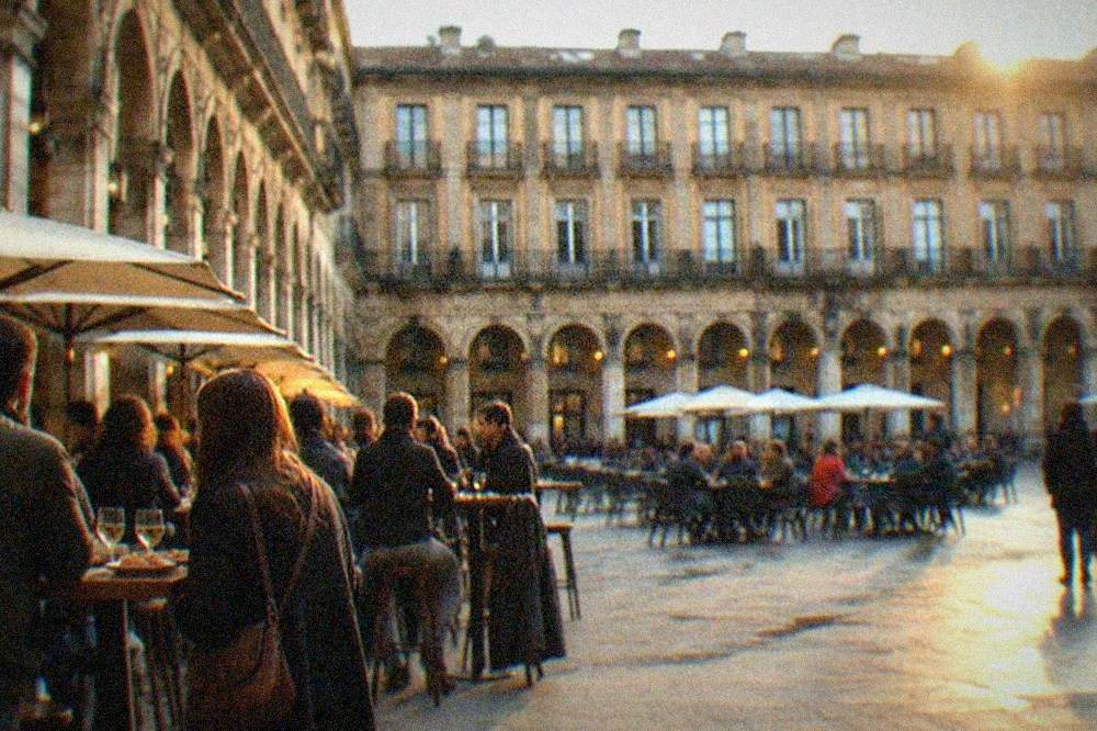 Golden evening light on the arcaded square of Plaza Nueva in Bilbao's old town with people at outdoor pintxos bars