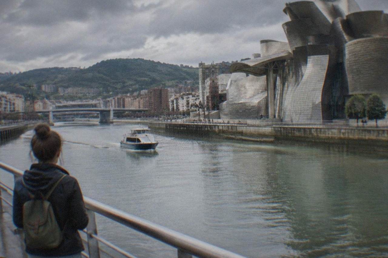 A single traveler with a small backpack looking out over the Guggenheim Museum and the Nervion river in Bilbao