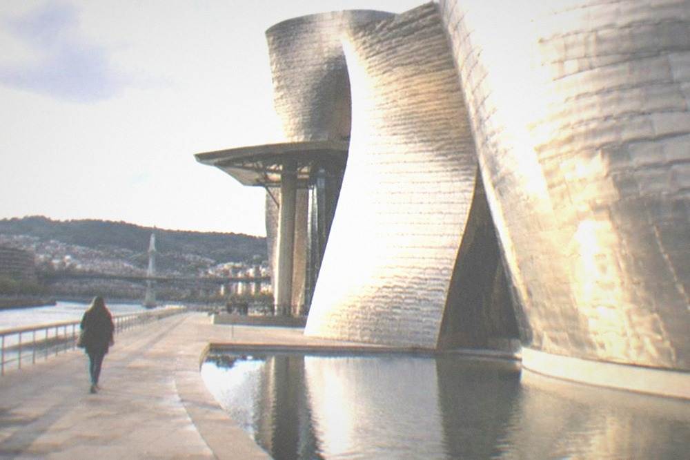 A lone visitor walking beside the titanium curves of the Guggenheim Museum in Bilbao