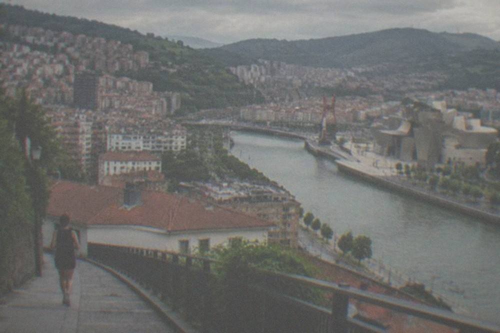 A wide view of Bilbao's rooftops and the river estuary in late summer afternoon light