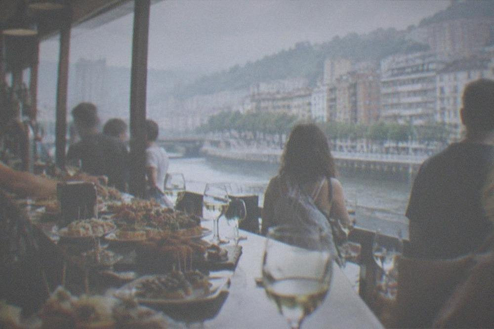 A bar counter crowded with small plates and glasses of wine in a busy pintxos bar