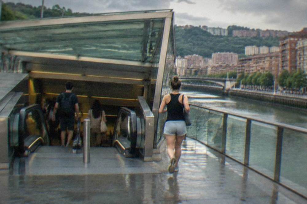 A modern metro station entrance in Bilbao with an escalator and passengers