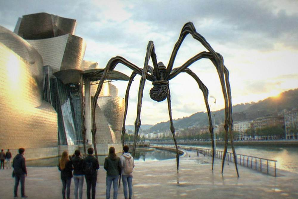 Teenagers looking up at the spider sculpture Maman outside the Guggenheim Museum in Bilbao