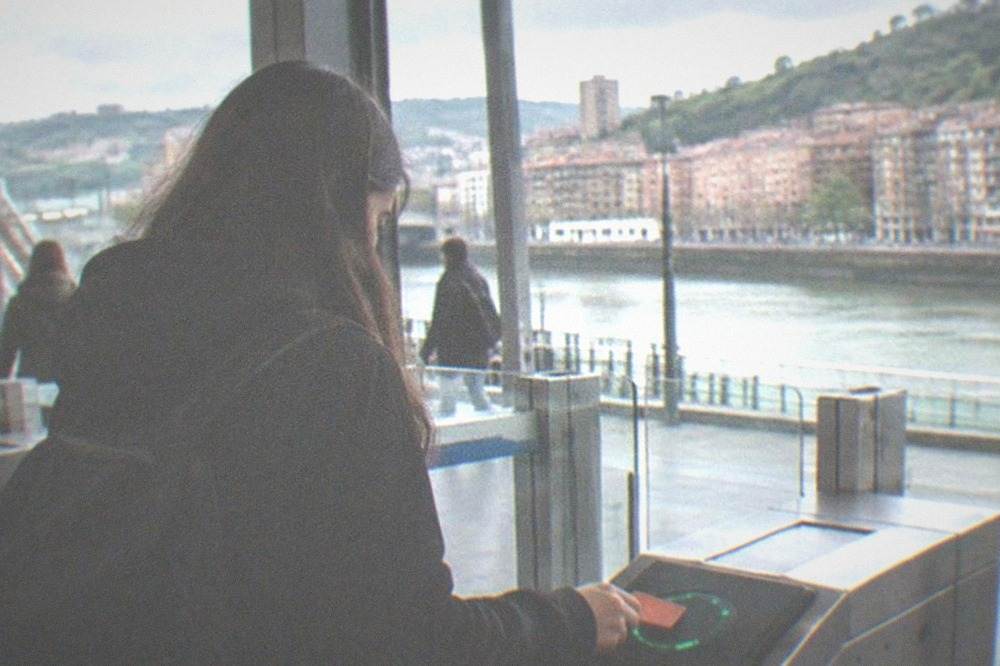 A teenager tapping a Barik card at a metro station validator in Bilbao