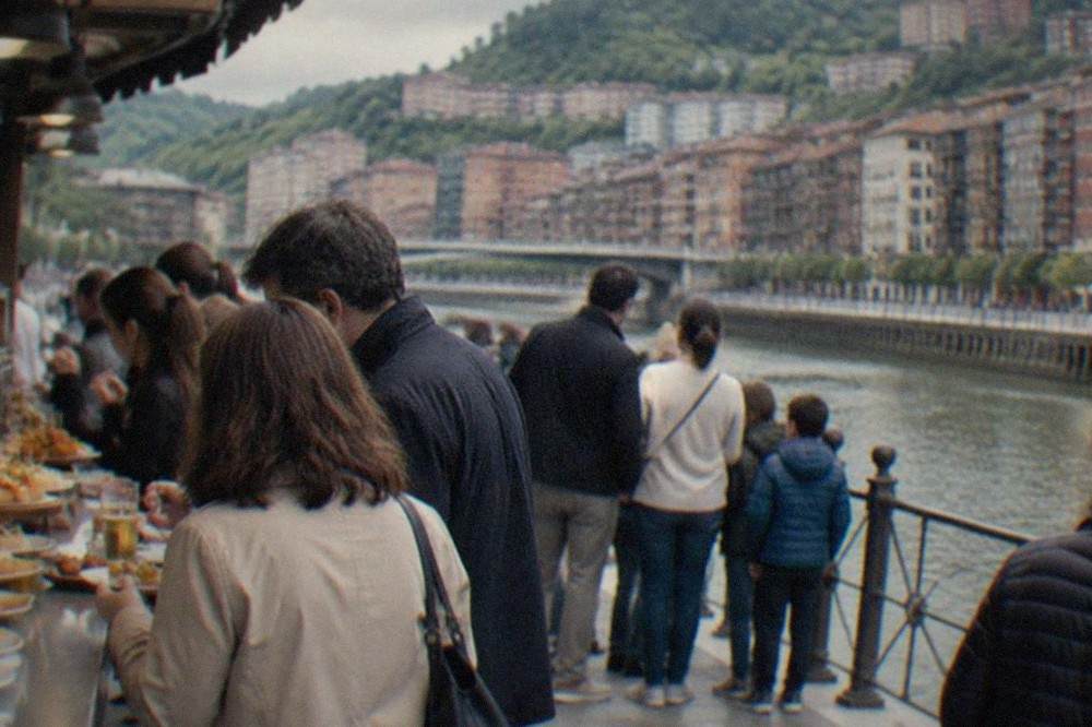A pintxos bar counter in Bilbao crowded with small plates and families standing to eat