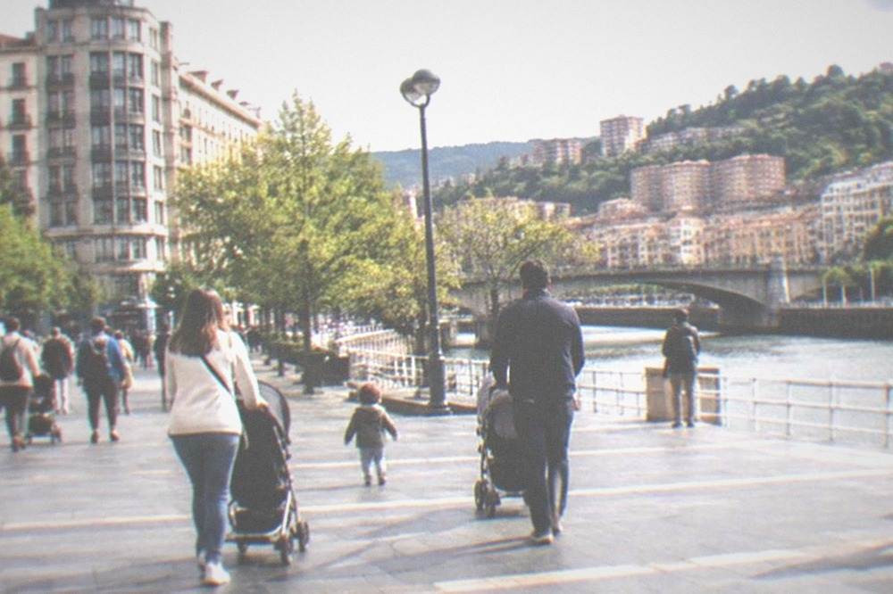 Families with pushchairs crossing a wide pedestrian square near the Moyua area of central Bilbao