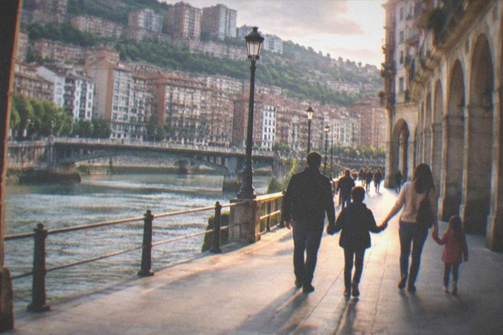 A family with children walking hand in hand toward the old town arcades of Bilbao at golden hour
