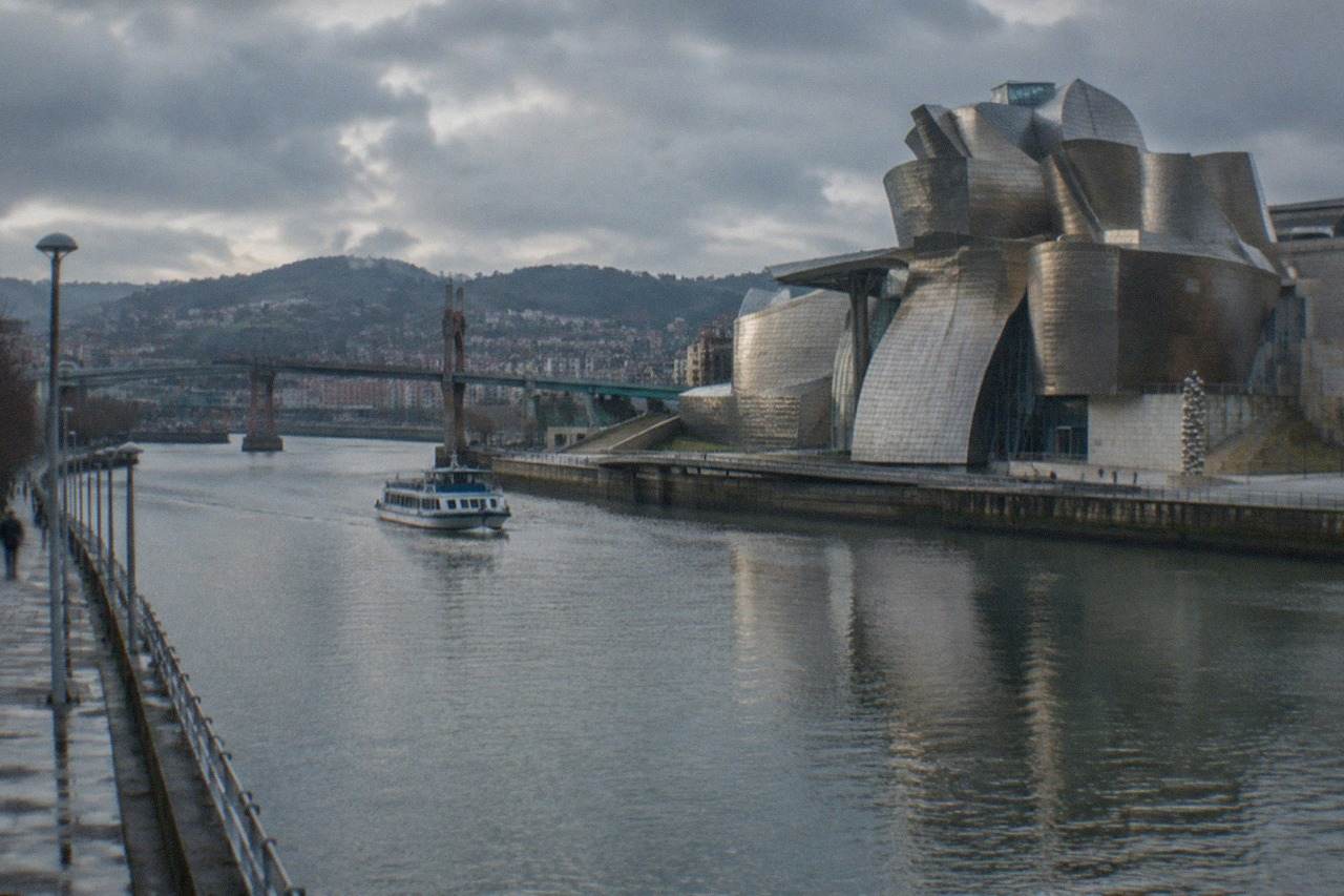 The Guggenheim Museum Bilbao's titanium curves reflecting on a wet day beside the Nervion estuary