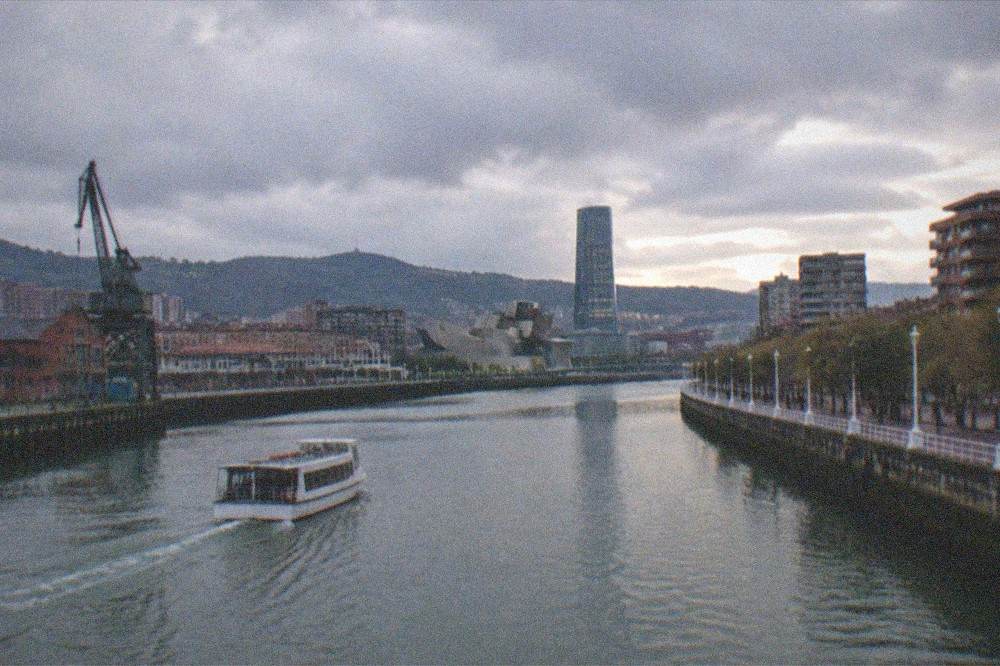 The Bilbao skyline at dusk seen across the Nervion river from a bridge