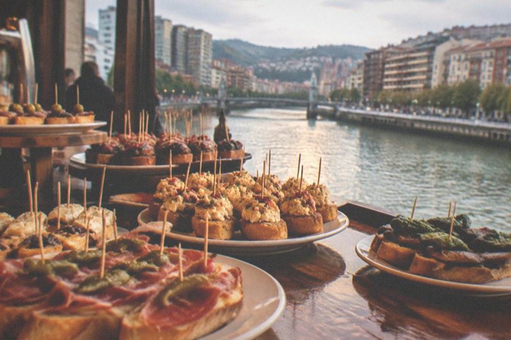 A counter covered with pintxos on skewers and small plates at a traditional Bilbao bar