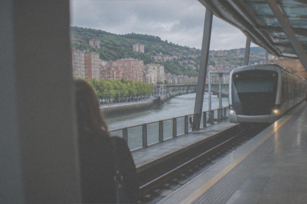 A Metro Bilbao station platform with a train arriving, showing the network's modern architecture